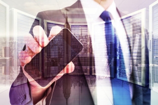 Businessman showing his smartphone screen against room with large window looking on city