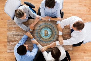 business team with bitcoin hologram holding hands
