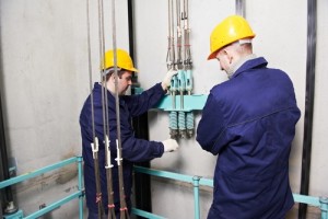 machinists adjusting lift in elevator hoistway