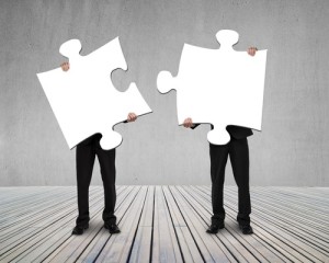 Businessmen holding two puzzles to connect