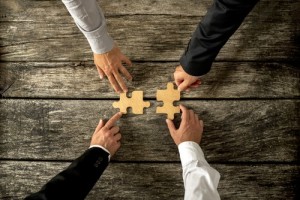 Four successful business men joining two puzzle pieces each bein
